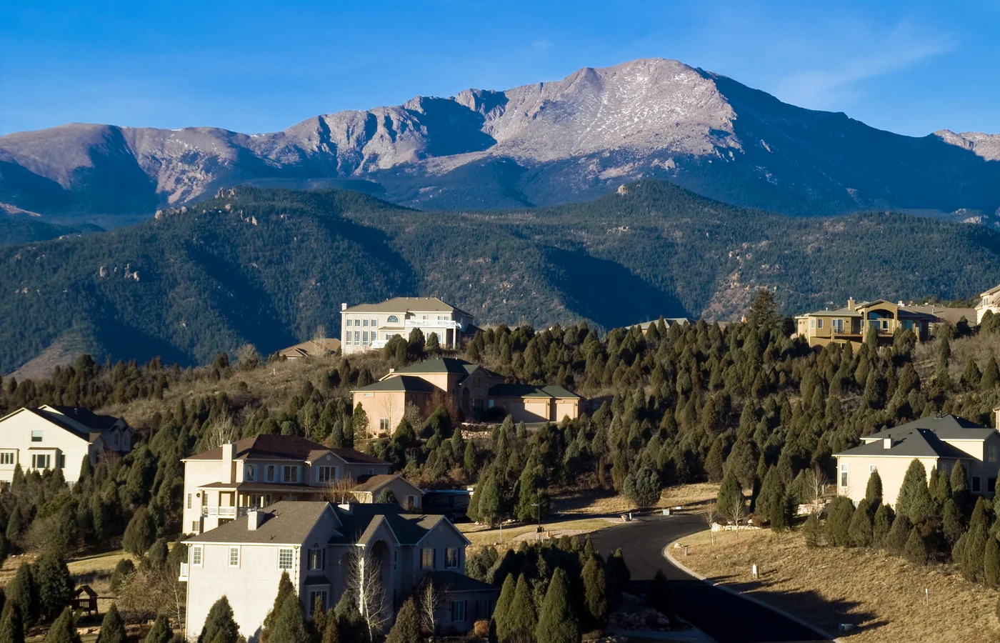 Luxury hillside homes below Pikes Peak in Colorado Springs, Colorado with pine-dotted foothills
